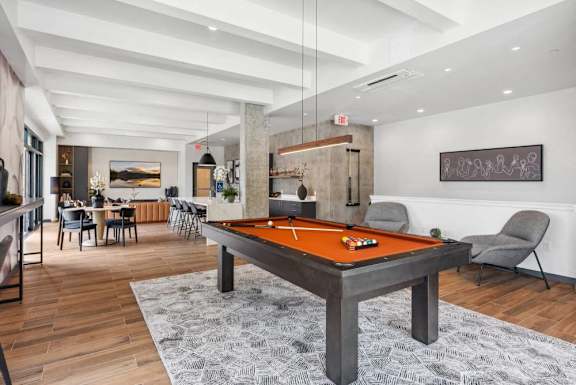 A billiard table is in the middle of a room with a grey rug.