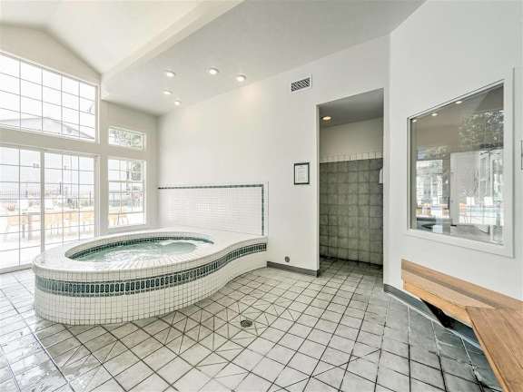 A modern bathroom with a jacuzzi tub and tiled floors.