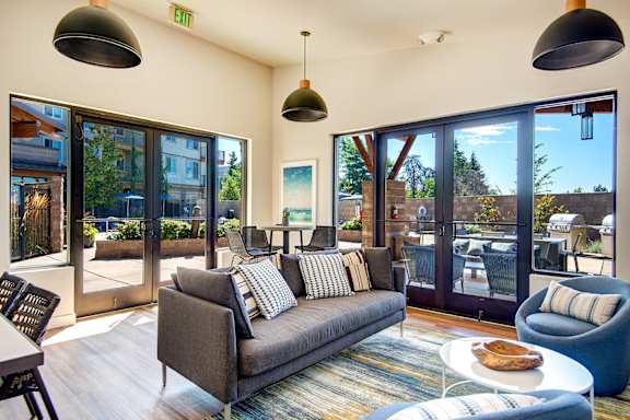 Living room with a couch and chairs and sliding glass doors at The Pacifica Apartments, Tacoma, WA