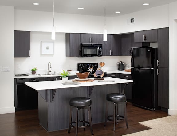 A modern kitchen with a white island and black appliances.