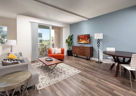 A modern living room with a grey sofa, a wooden coffee table, and a grey and white patterned rug.