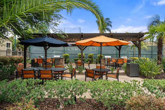 A patio with tables and chairs under umbrellas.