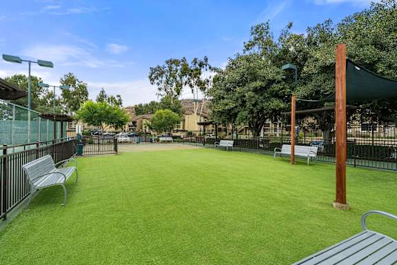 A park with a green lawn and a wooden pole.