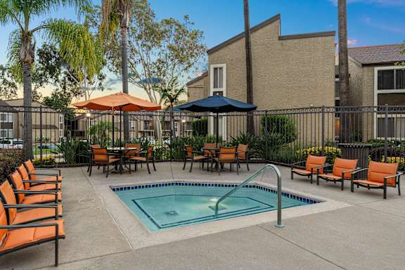 A pool surrounded by orange chairs and umbrellas.