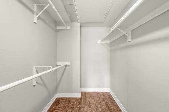 A room with white walls and wooden flooring with white shelving.