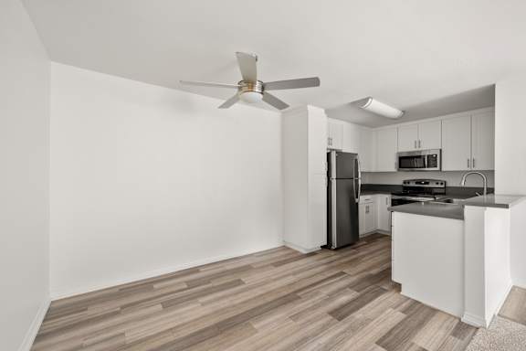 A kitchen with a refrigerator, microwave, and stove top oven.