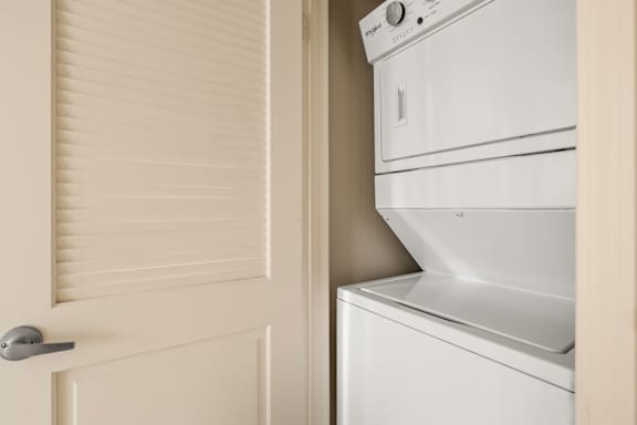 A white washing machine sits next to a white door with a silver handle.