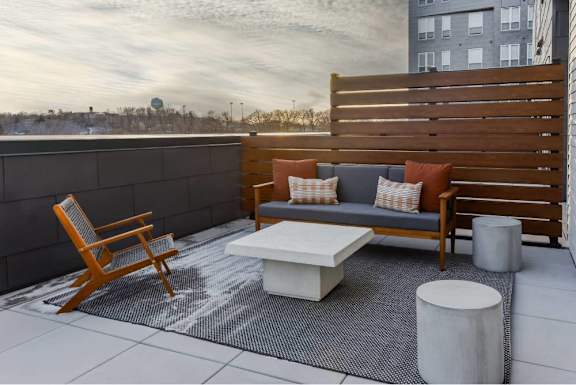 A wooden chair and a white table are on a patio.