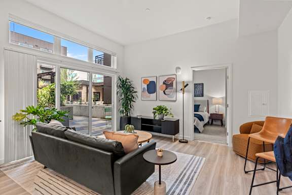 A living room with a black couch and a wooden floor.