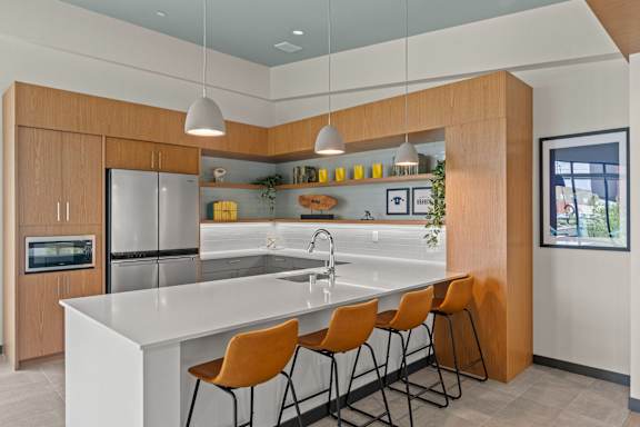 A modern kitchen with a white countertop and orange chairs.