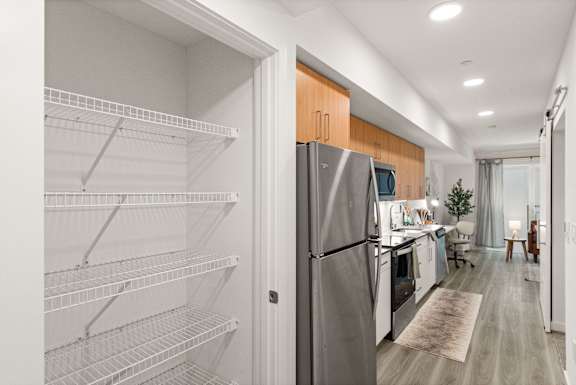 A modern kitchen with a refrigerator and empty shelves.