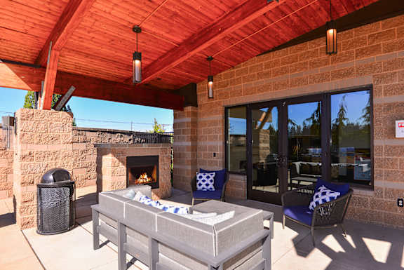 Outdoor patio has a fireplace and a table with chairs at The Pacifica Apartments, 98409