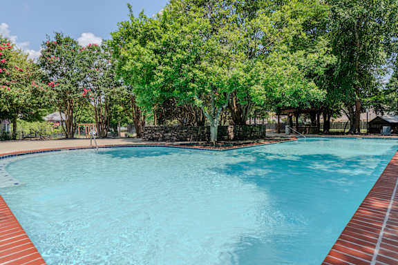 A swimming pool surrounded by trees and a fence.