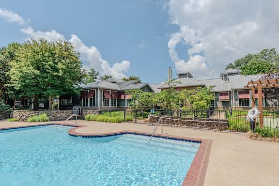 A swimming pool surrounded by a fence and a building in the background.