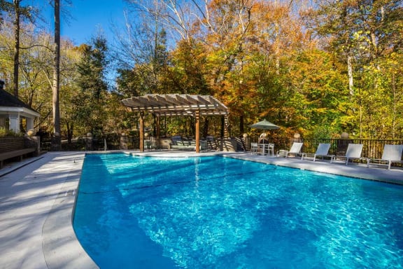a swimming pool with a pergola and chairs