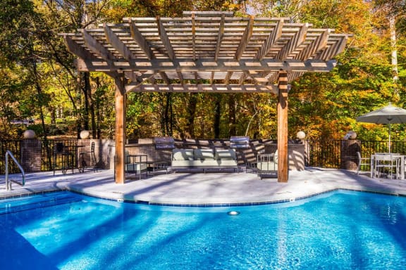 a swimming pool with a wooden pergola next to it