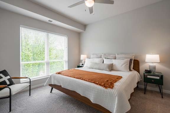 A bedroom with a large bed and a chair by the window.