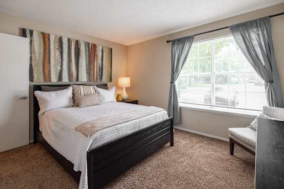 A bedroom with a large bed and a chair.