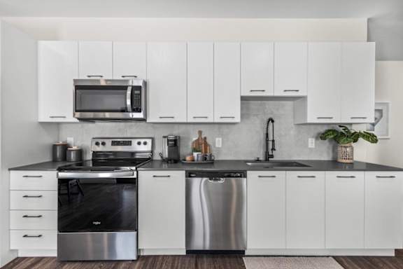 A modern kitchen with white cabinets and stainless steel appliances.