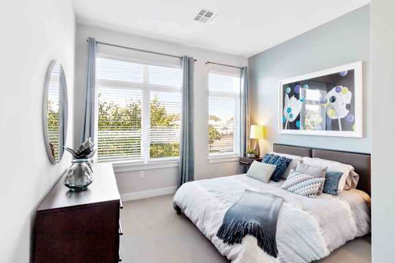 A bedroom with a large bed and a window with blinds.