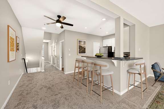 A spacious kitchen and bar area with a ceiling fan and lighting.