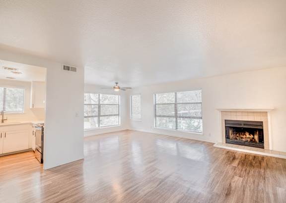 A large, empty room with a fireplace and wooden floors.