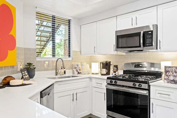 A modern kitchen with white cabinets and a black stove top oven.