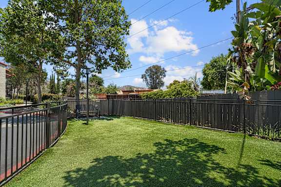 A backyard with a green lawn and a fence.