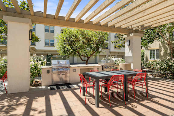 A patio with grills and a table and chairs