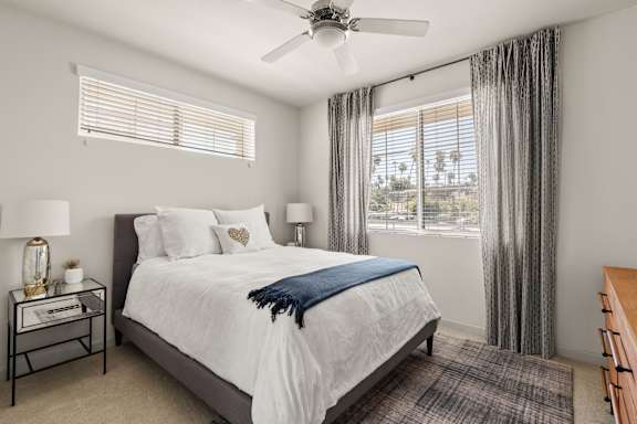 A bedroom with a large bed and a ceiling fan.