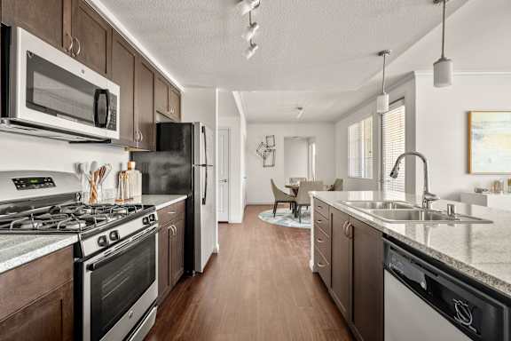 A spacious and modern kitchen with dark wood cabinets and black and stainless steel appliances.