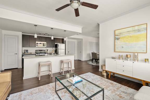 A modern kitchen with a kitchen island  area and a living room with a sofa.
