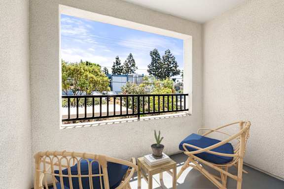 A balcony with a chair and a table with a potted plant on it.