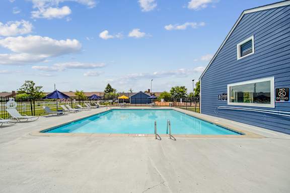 A blue swimming pool in front of a grey building.
