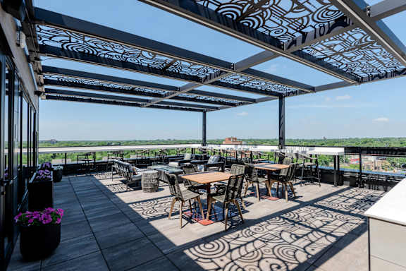 A patio with tables and chairs under a patterned awning.