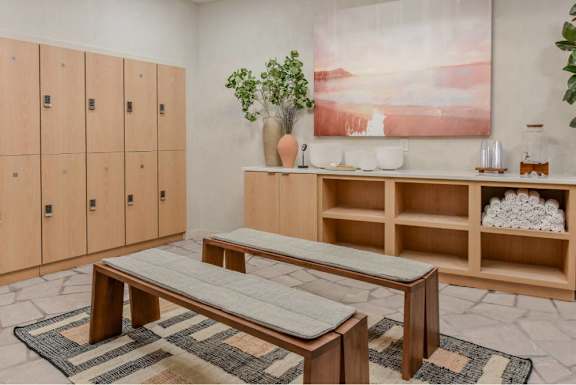 A room with a bench, a cabinet, and a painting on the wall.
