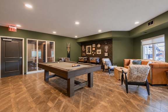 A room with a pool table and couches.
