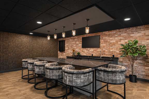 A room with a long table and chairs with a brick wall in the background.