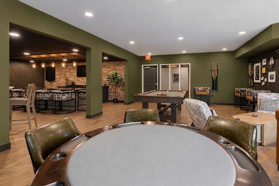 A large oval table is surrounded by chairs in a room with a brick wall.