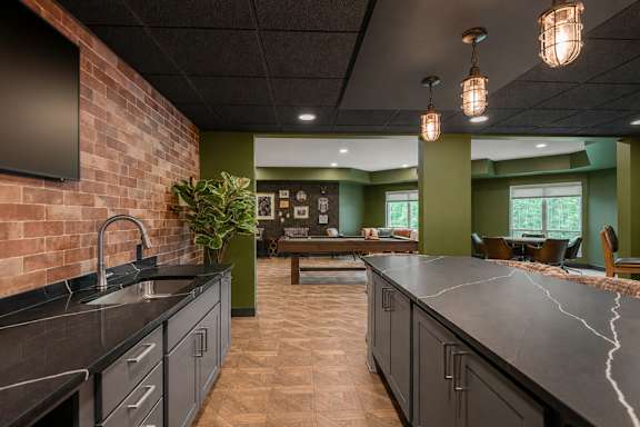 A kitchen with a black counter top and a brick wall.