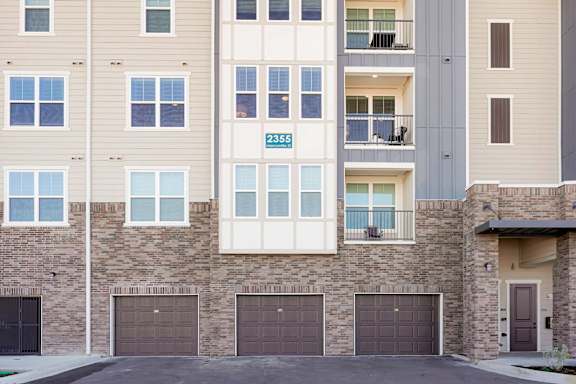 Apartment building with garage doors and balconies.