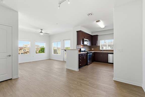 A spacious kitchen with wooden floors and white walls.