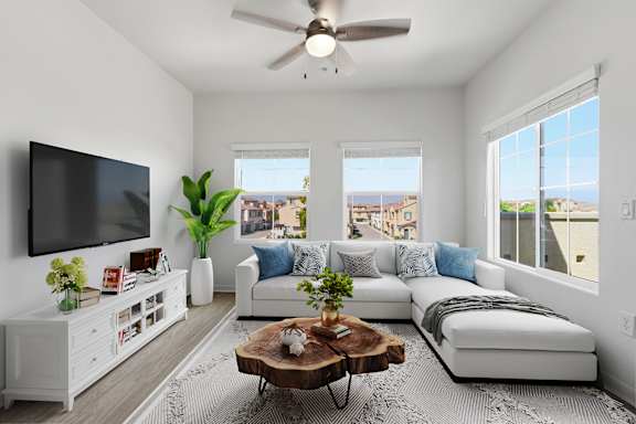 A living room with a white couch, a wooden coffee table, and a flat-screen TV mounted on the wall.