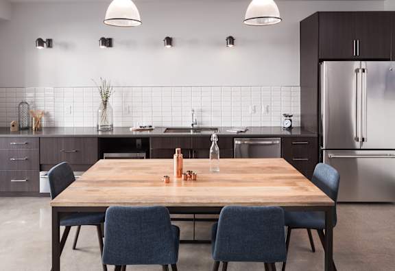 A modern kitchen with a wooden table and blue chairs.