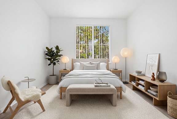 A bedroom with a large bed, a chair, and a plant.