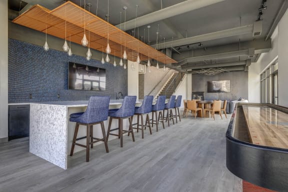 a lobby with bar stools and chairs and a bar and a table with chairs