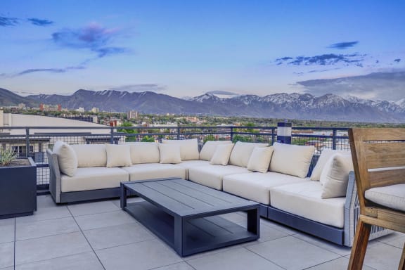 a patio with couches and a table on a balcony overlooking the mountains