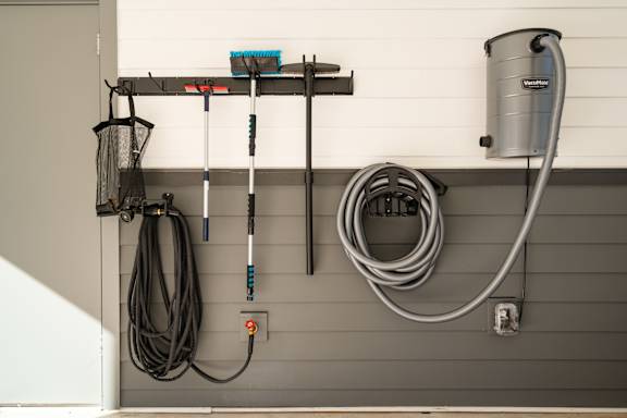 A wall-mounted rack holds a broom, mop, and dustpan.