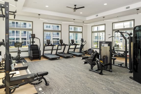 a gym with treadmills and other exercise equipment in a building with windows