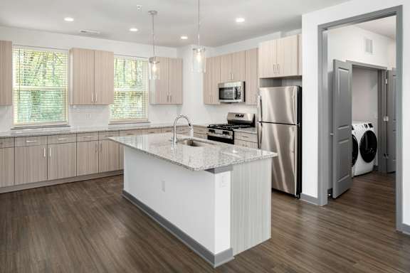 A modern kitchen with wooden floors and a white island.